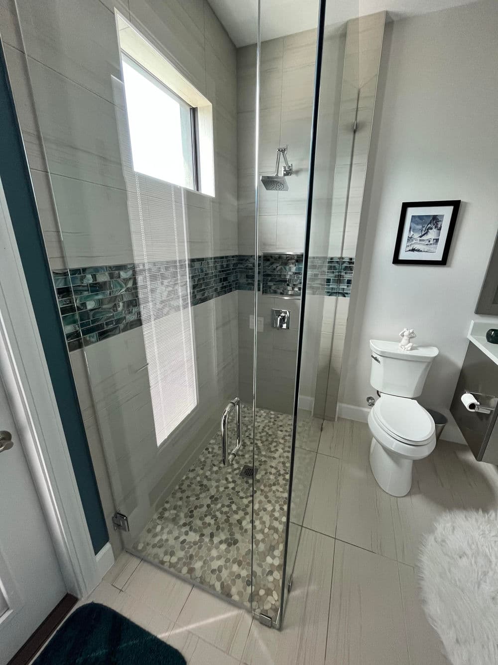 Modern glass shower with mosaic tiles and a white toilet in a stylish bathroom setting.
