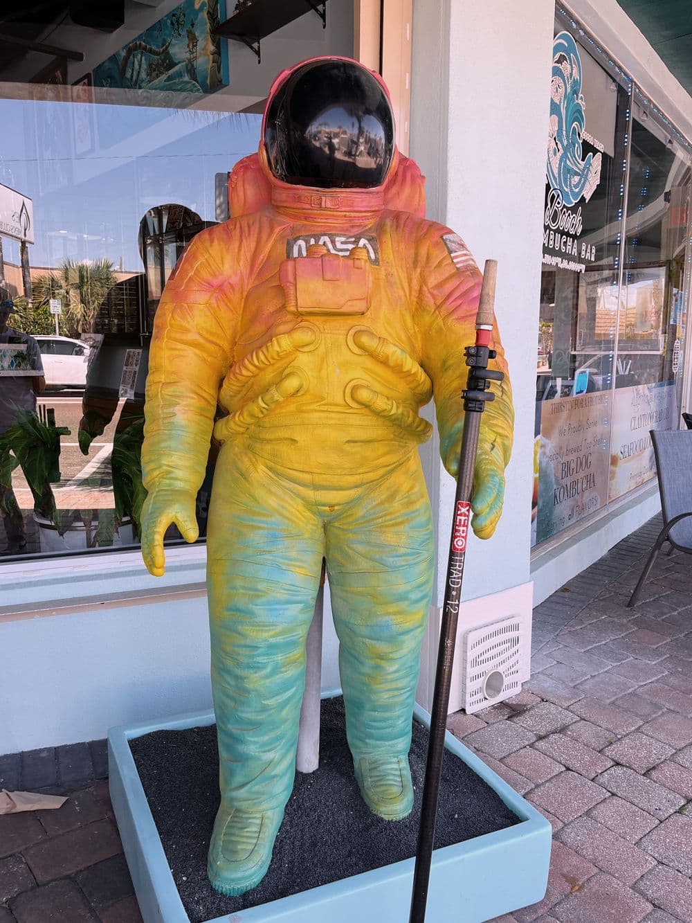 Colorful astronaut statue in front of a shop, showcasing NASA insignia and vibrant gradients.