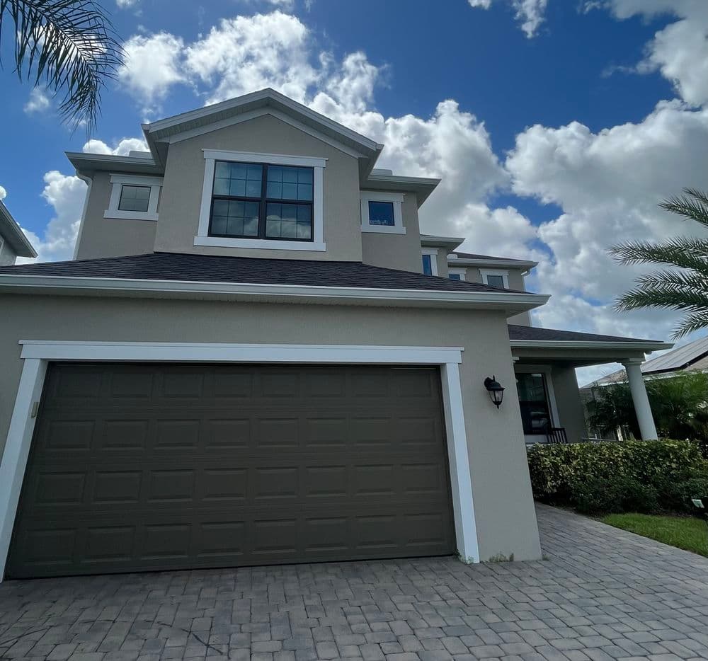 Modern two-story house with a garage and scenic blue sky in the background.