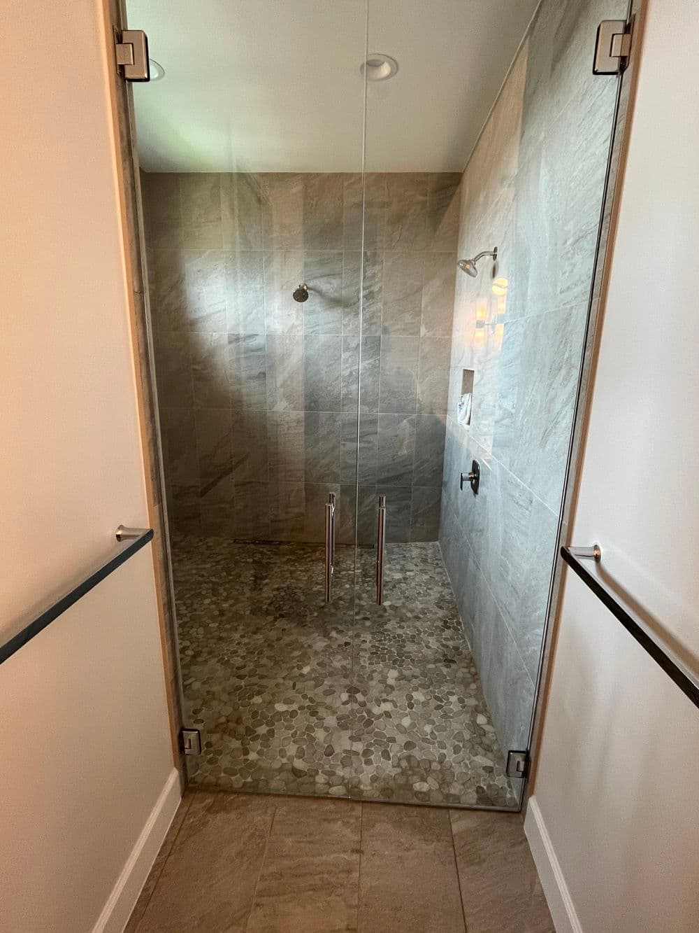 Modern glass shower enclosure with natural stone tiles and sleek fixtures.