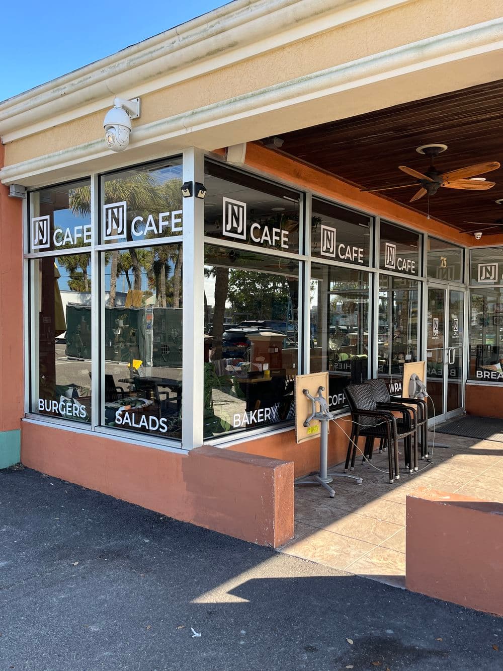 View of NJ Cafe exterior featuring large windows and a menu of burgers, salads, and bakery items.