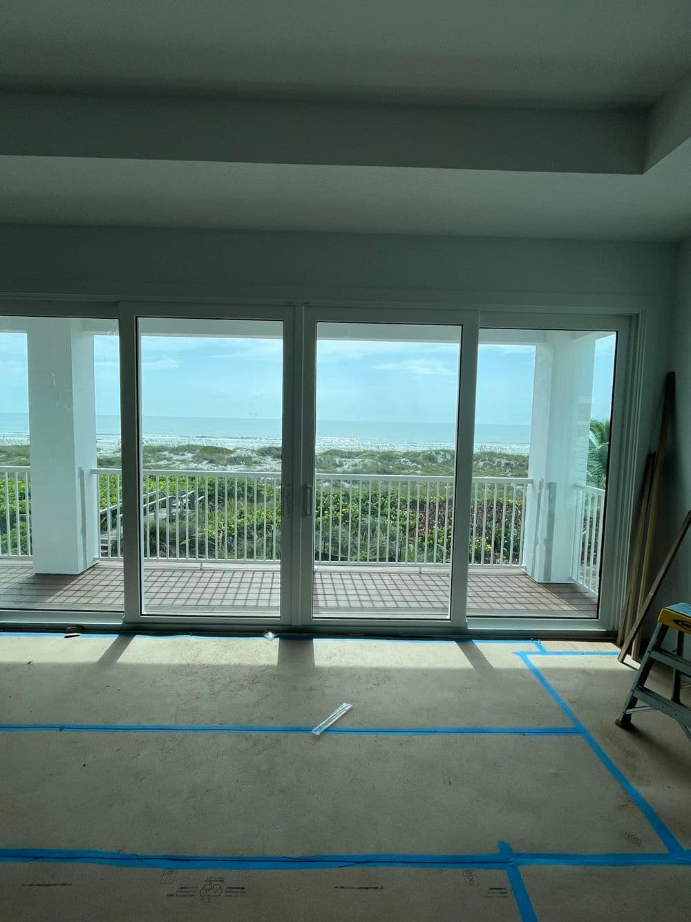Ocean view from large sliding glass doors in a bright, modern room under renovation.