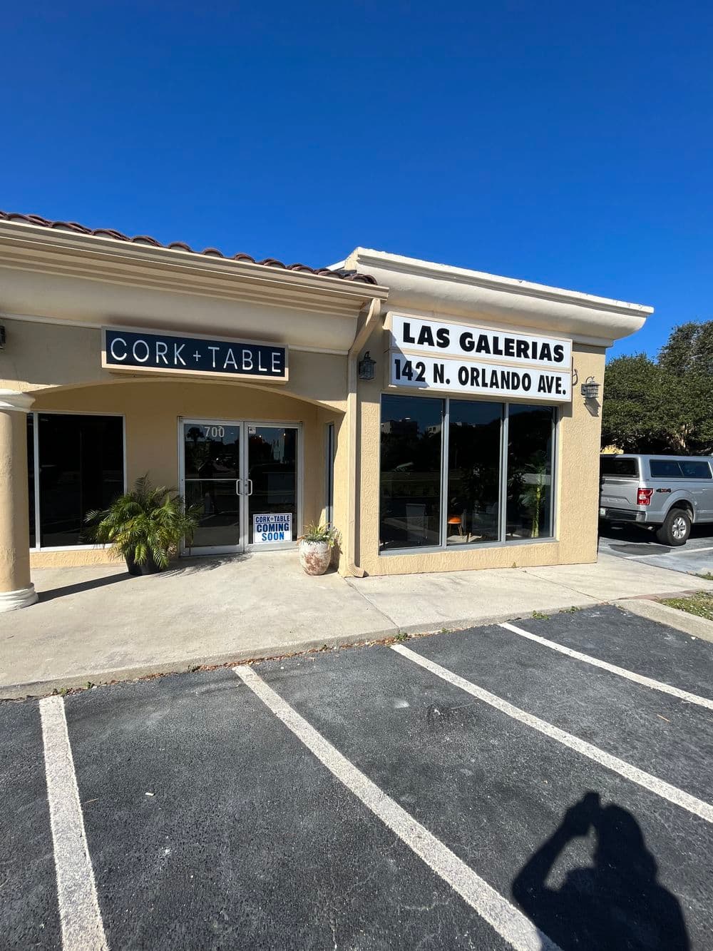 Cork + Table and Las Galerias storefront on Orlando Avenue, with clear sunny sky.