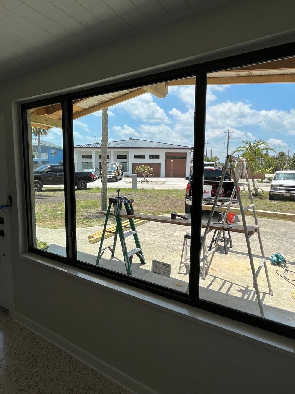 View from inside a room showing a large window with outdoor construction and tools visible.